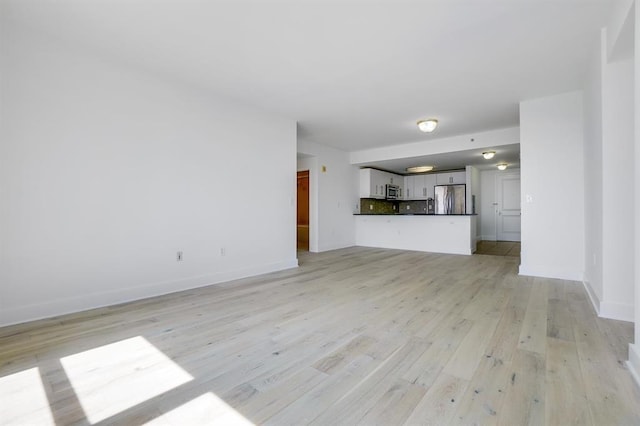 unfurnished living room with light wood-style flooring and baseboards