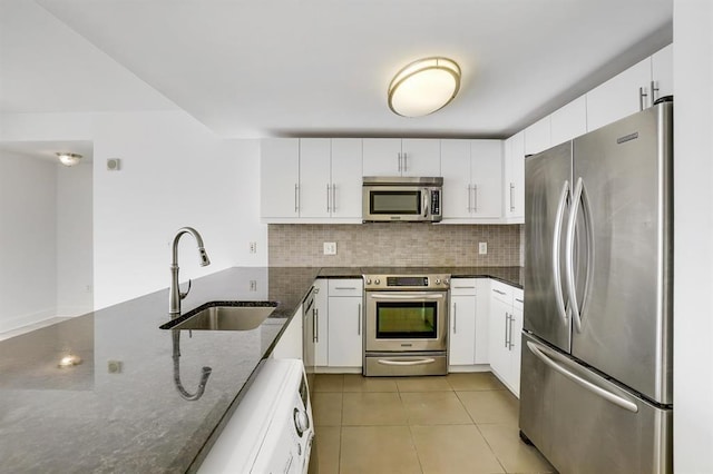 kitchen featuring tasteful backsplash, appliances with stainless steel finishes, dark stone counters, and a sink