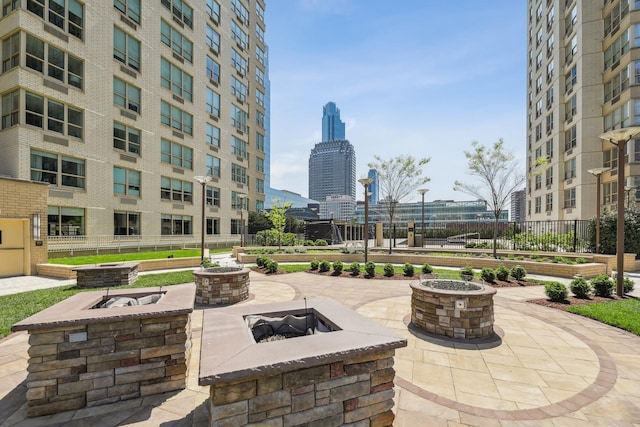 view of patio / terrace with a view of city, fence, and an outdoor fire pit