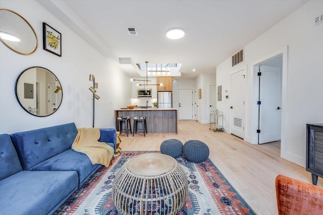 living room with light hardwood / wood-style floors and sink