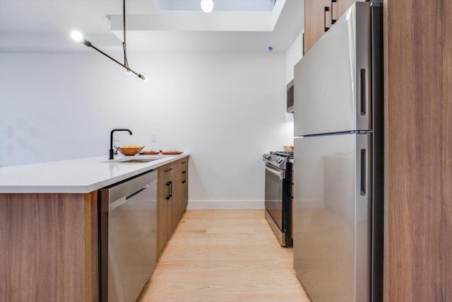 kitchen with kitchen peninsula, stainless steel appliances, light hardwood / wood-style flooring, and sink