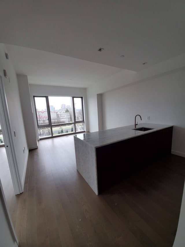 kitchen featuring wood-type flooring, visible vents, a sink, light stone countertops, and baseboards