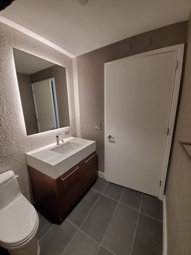 half bath featuring vanity, tile patterned flooring, and toilet