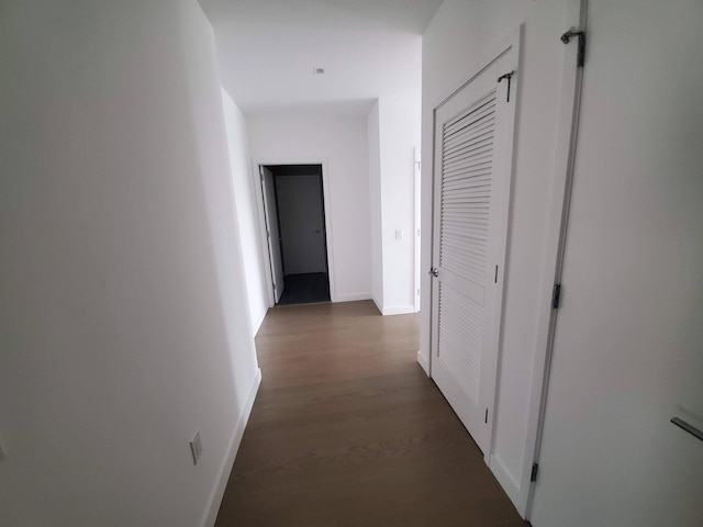 hall featuring dark wood-type flooring and baseboards