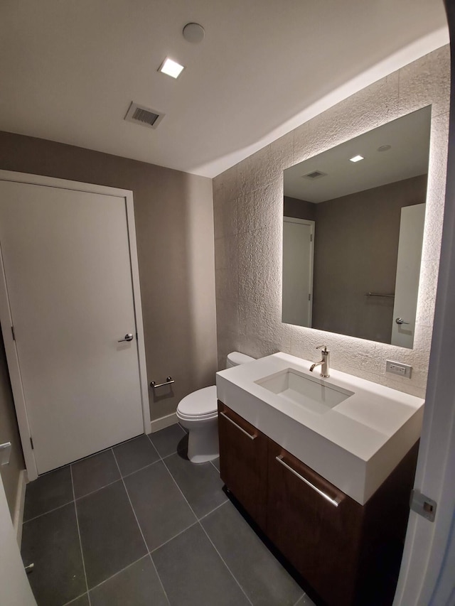 bathroom featuring a textured wall, tile patterned flooring, toilet, visible vents, and vanity