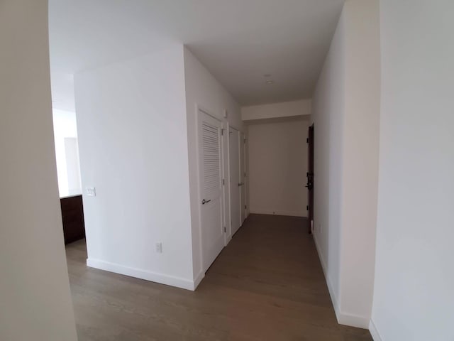 corridor with wood finished floors and baseboards