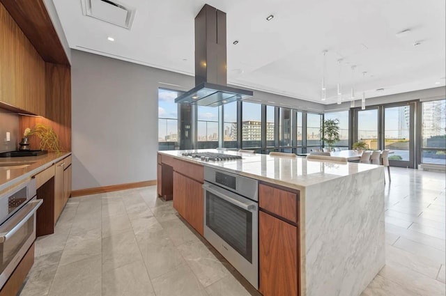 kitchen with light stone countertops, appliances with stainless steel finishes, island range hood, hanging light fixtures, and a large island