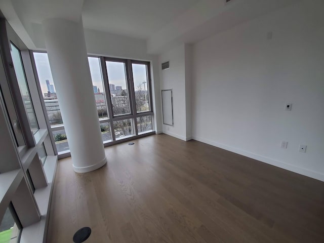 empty room with baseboards, a view of city, visible vents, and wood finished floors