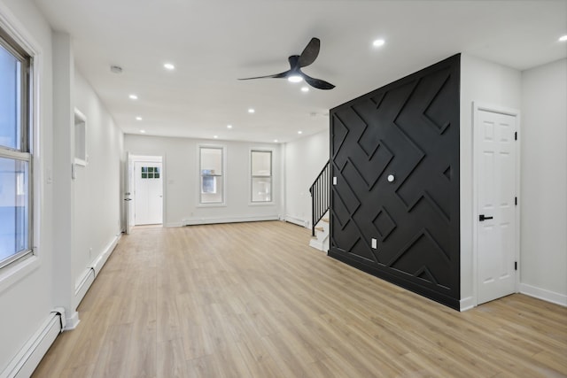 unfurnished living room featuring light wood-style floors, stairs, a baseboard heating unit, and recessed lighting