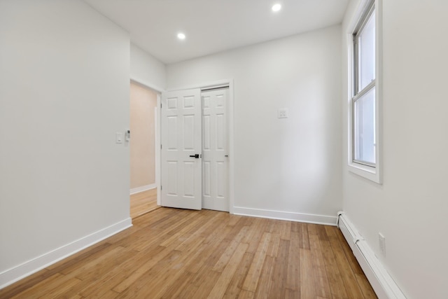 unfurnished room with light wood finished floors, a baseboard radiator, recessed lighting, and baseboards