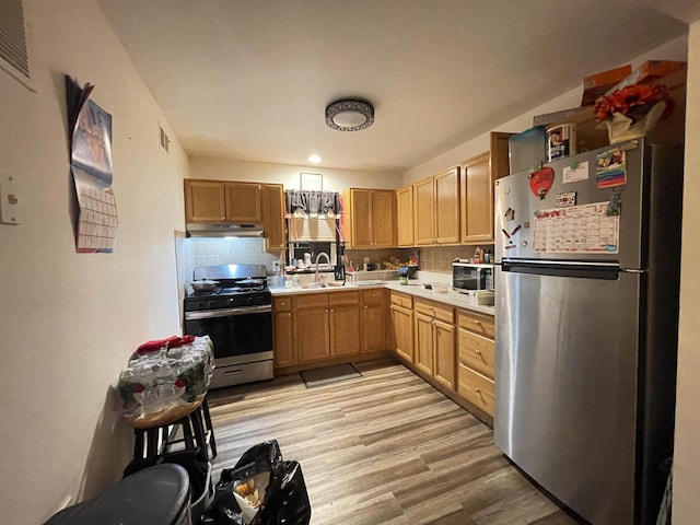 kitchen with sink, decorative backsplash, stainless steel appliances, and light hardwood / wood-style floors