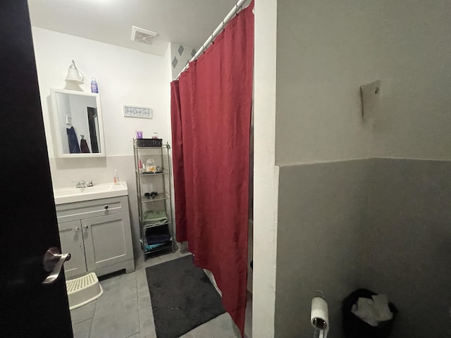 bathroom with walk in shower, vanity, and tile patterned flooring