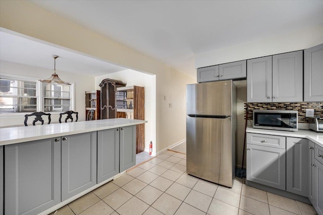 kitchen with gray cabinetry, backsplash, light tile patterned flooring, and stainless steel appliances