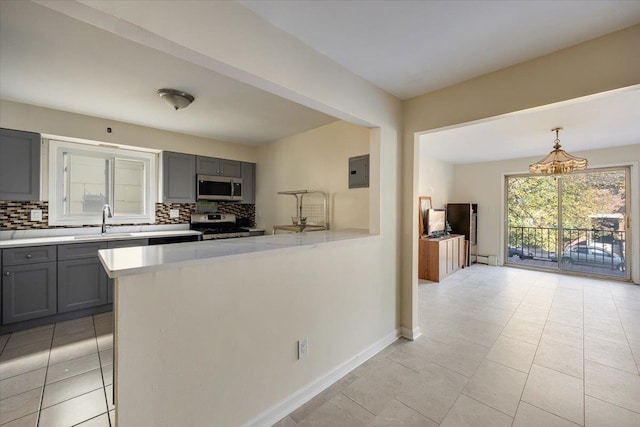 kitchen featuring pendant lighting, kitchen peninsula, backsplash, and appliances with stainless steel finishes