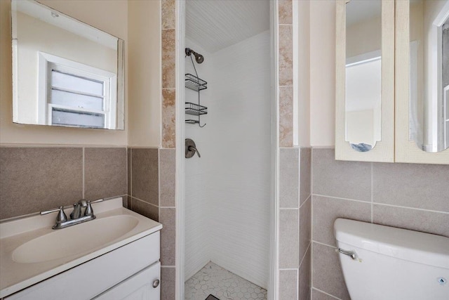 bathroom featuring tile walls, a tile shower, vanity, and toilet