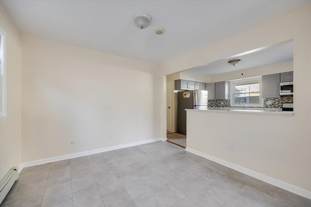 kitchen featuring stainless steel appliances, gray cabinets, sink, decorative backsplash, and a baseboard heating unit