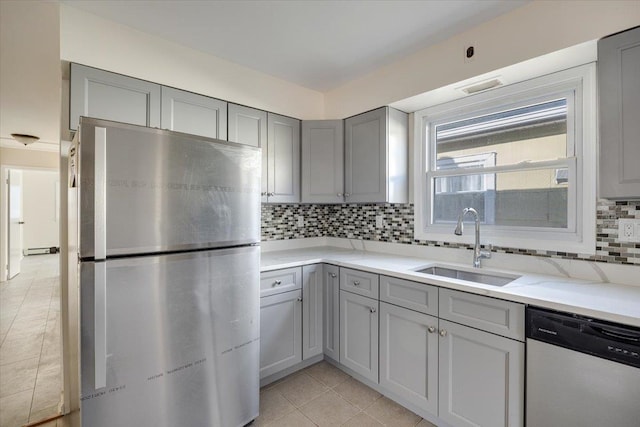 kitchen featuring gray cabinetry, backsplash, appliances with stainless steel finishes, light stone countertops, and sink