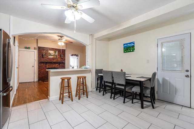 dining area featuring vaulted ceiling, light wood-style floors, arched walkways, and ceiling fan