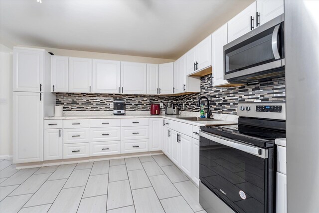 kitchen featuring decorative backsplash, appliances with stainless steel finishes, light countertops, and a sink