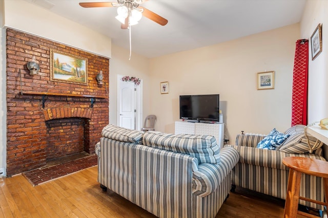 living room with visible vents, a brick fireplace, a ceiling fan, and hardwood / wood-style flooring