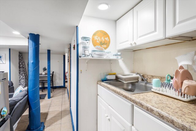 kitchen featuring white cabinetry, light countertops, light tile patterned flooring, and a sink