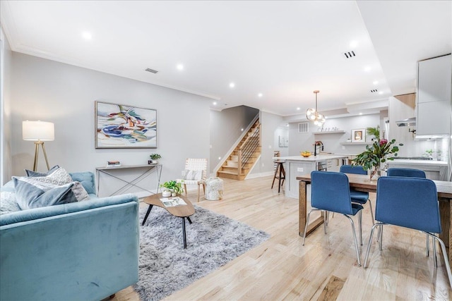 living room with light hardwood / wood-style flooring, ornamental molding, and sink