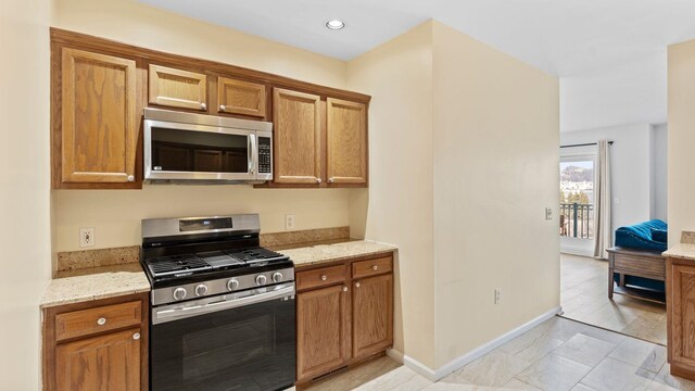 344 The Promenade Unit 344, Edgewater, NJ 07020 - kitchen with brown cabinets, light stone countertops, stainless steel appliances, recessed lighting, and baseboards