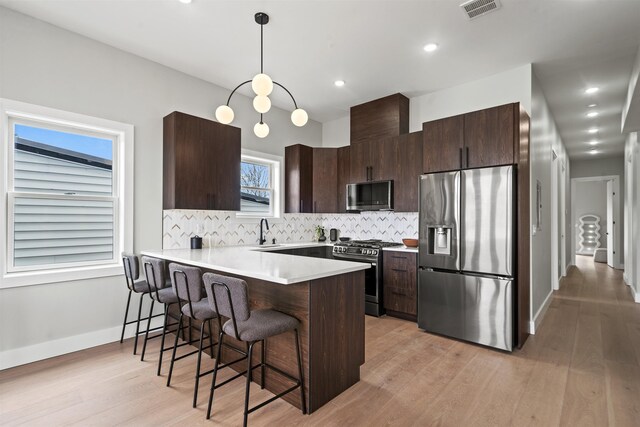28 Cambridge Ave Unit 2, Jersey City, NJ 07307 - kitchen with visible vents, a peninsula, a breakfast bar, dark brown cabinets, and appliances with stainless steel finishes