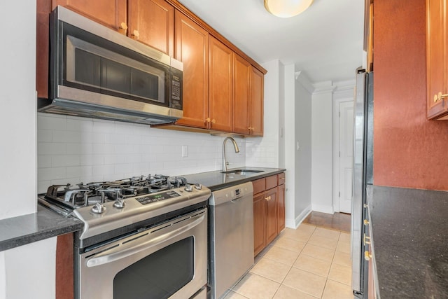 kitchen with dark stone countertops, stainless steel appliances, light tile patterned floors, sink, and backsplash