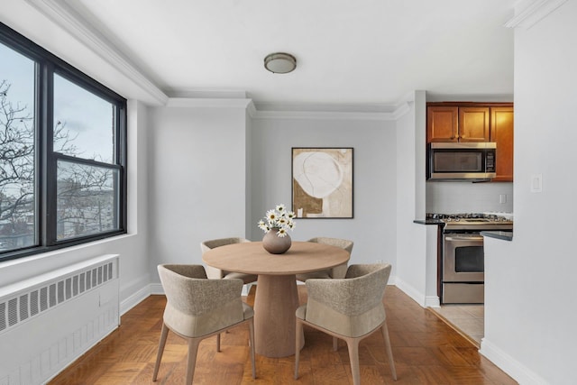 dining area featuring a healthy amount of sunlight, light parquet flooring, crown molding, and radiator heating unit