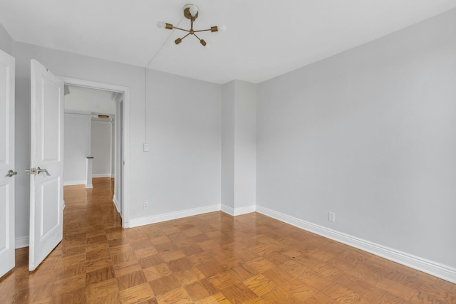 unfurnished room with a chandelier and parquet flooring