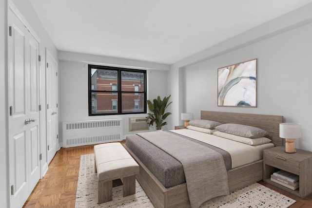 bedroom with light parquet flooring, a wall mounted AC, and radiator