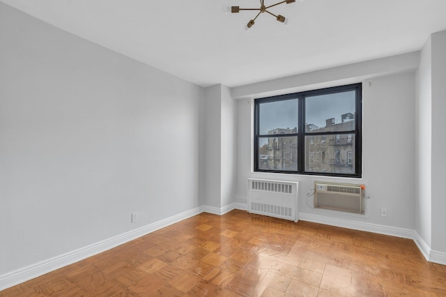 unfurnished room with light parquet flooring, an inviting chandelier, a wall mounted air conditioner, and radiator