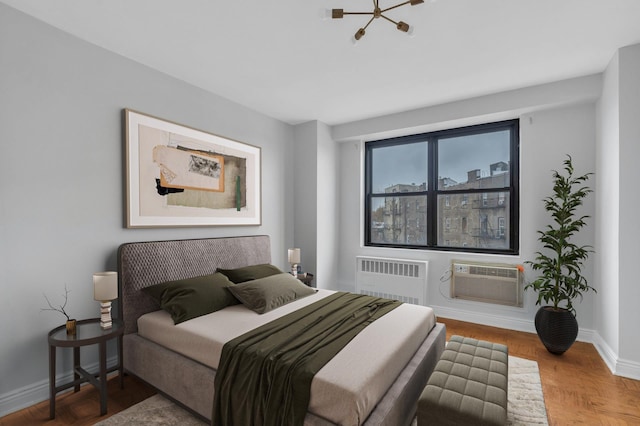 bedroom featuring a wall mounted AC, an inviting chandelier, radiator heating unit, and parquet flooring