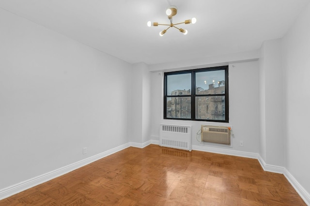 empty room featuring a wall mounted AC, a notable chandelier, radiator, and parquet flooring