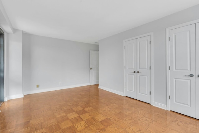 unfurnished bedroom with two closets and light parquet floors