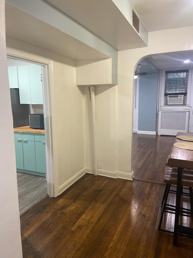 interior space featuring radiator heating unit, cooling unit, and dark wood-type flooring