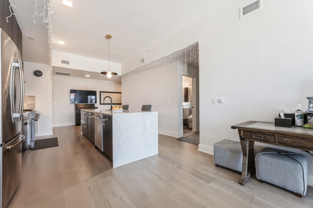 kitchen with light wood-type flooring, visible vents, light countertops, and freestanding refrigerator