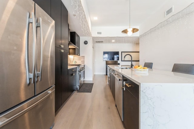 kitchen with visible vents, a sink, stainless steel appliances, modern cabinets, and light wood-type flooring