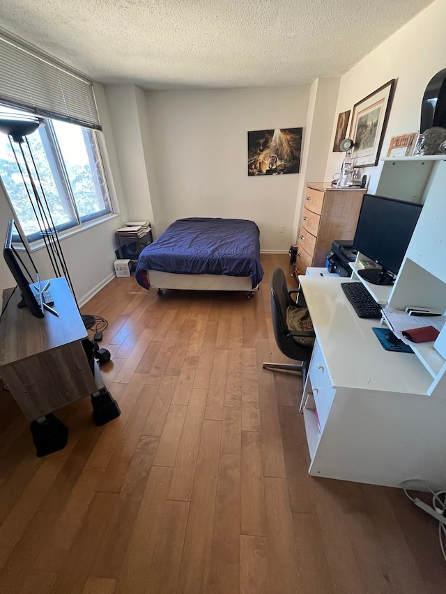 bedroom featuring a textured ceiling, baseboards, and hardwood / wood-style floors