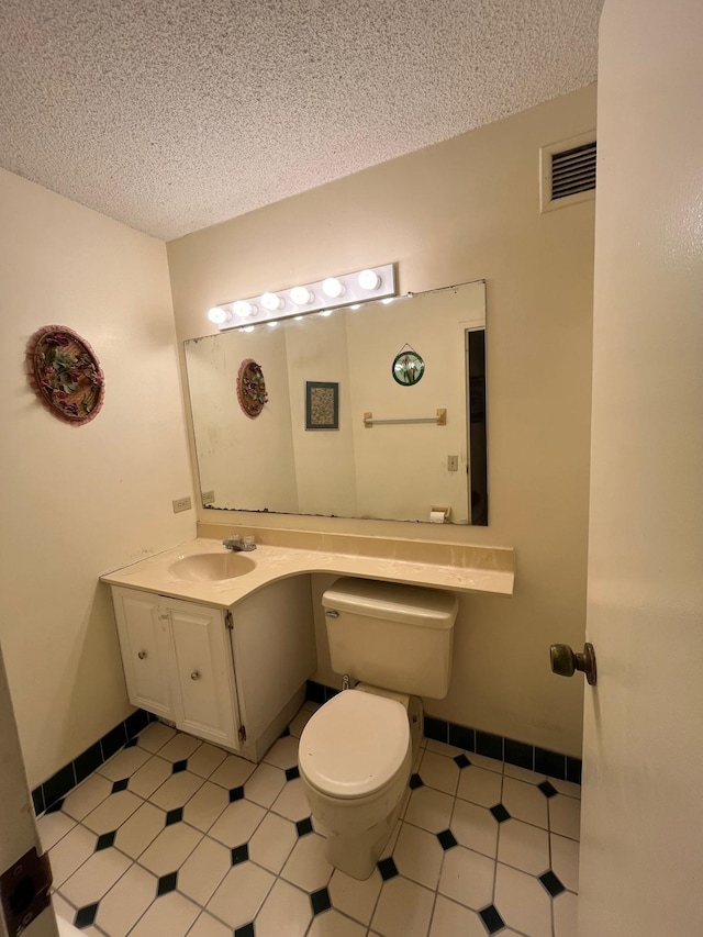 bathroom featuring visible vents, toilet, a textured ceiling, baseboards, and vanity