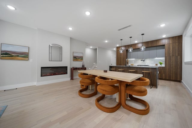 45 Graham St Unit 1, Jersey City, NJ 07307 - dining room featuring light wood-style floors, a glass covered fireplace, and recessed lighting