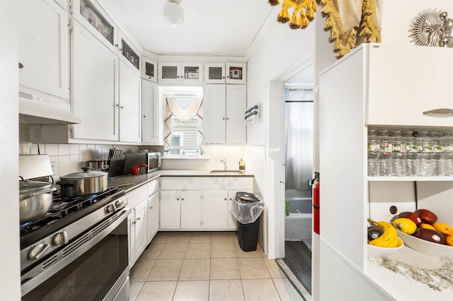 kitchen featuring stainless steel appliances, under cabinet range hood, white cabinetry, decorative backsplash, and light tile patterned floors