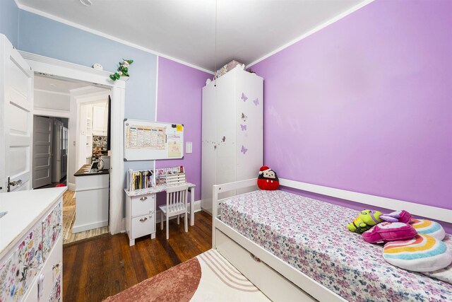 bedroom with dark wood finished floors and crown molding