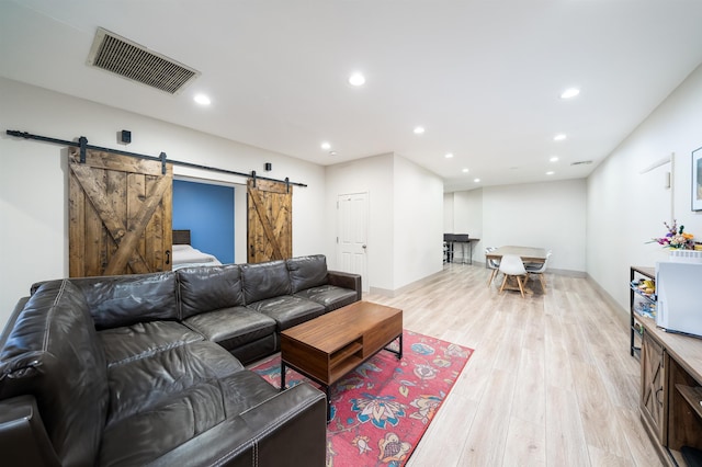 living room with a barn door and light hardwood / wood-style flooring