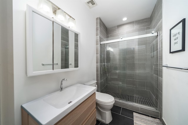 bathroom featuring tile patterned flooring, vanity, toilet, and a shower with door