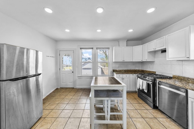 kitchen featuring light tile patterned floors, white cabinets, recessed lighting, dark countertops, and stainless steel appliances