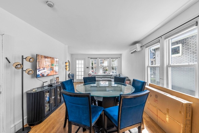 dining area featuring light wood-style flooring and a wall mounted air conditioner