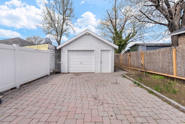 detached garage featuring driveway and fence