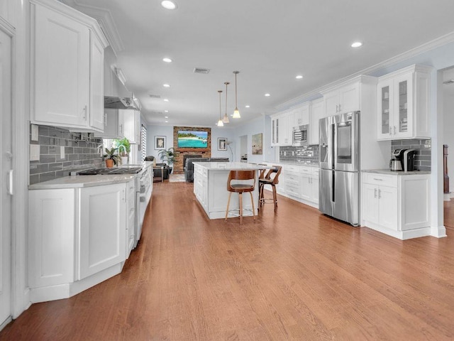 183 Oak Ave, River Edge, NJ 07661 - kitchen featuring appliances with stainless steel finishes, a stone fireplace, white cabinets, a kitchen island, and open floor plan